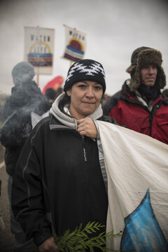 Dani from Montana holds cedar, a sign of peace while being blessed and cleansed by a cloud of Sage at a peaceful protest near one of the barricades.