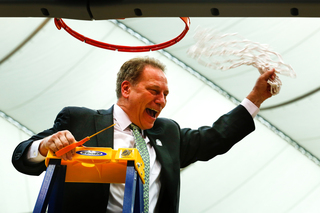 Michigan State head coach Tom Izzo waves the net in the air as spectators cheer.